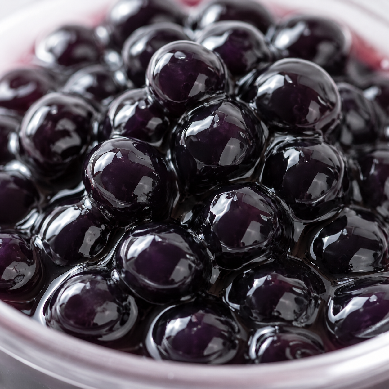 Close-up of Blueberry Frubo Popping Boba featuring glossy juice-filled bursting pearls with vibrant sweet-tart blueberry flavor for bubble tea and dessert applications.