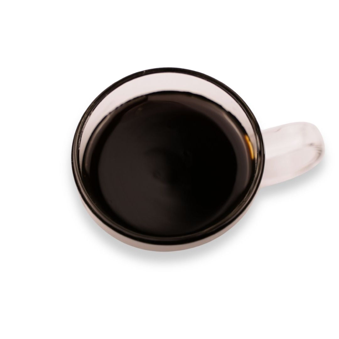Dark purple grape flavored syrup in a glass cup on a white background