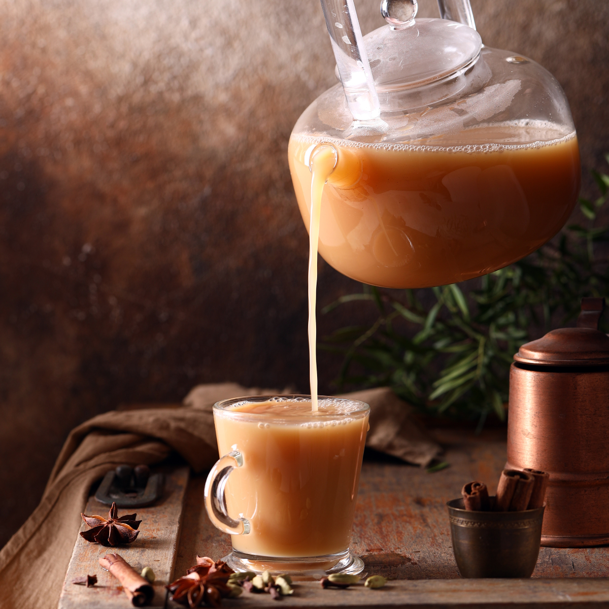 Freshly prepared chai milk tea with black tea cinnamon cardamom and warming spices in a cozy café setting