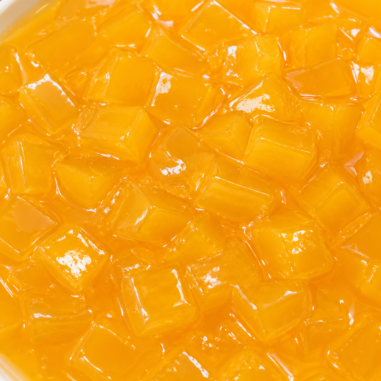 Close-up of Mango Nata de Coco Jelly highlighting translucent chewy coconut jelly cubes coated in sweet tropical mango syrup for beverages and desserts.